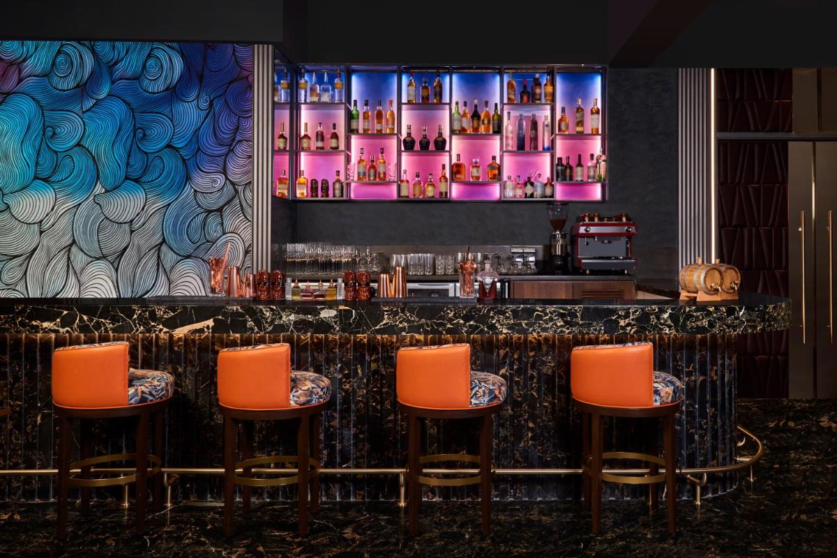 a bar with orange chairs and a large screen at Novotel Mumbai International Airport in Mumbai