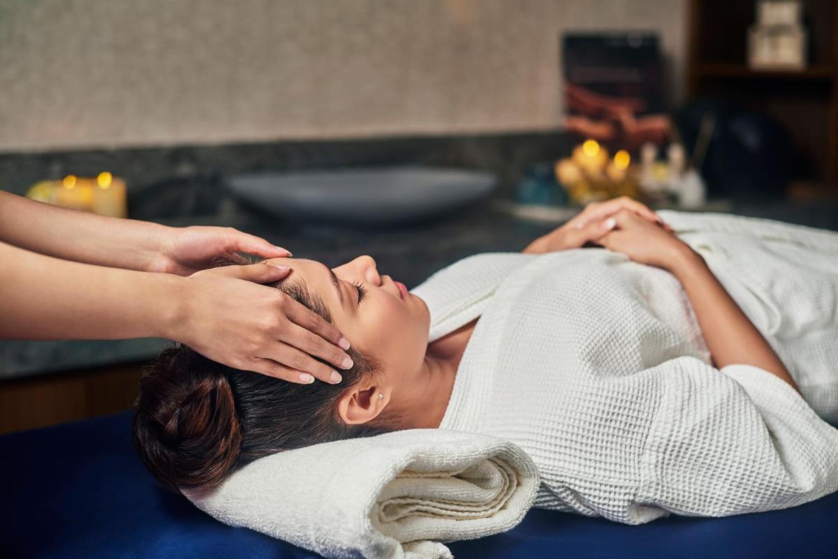 a woman getting a massage from a massage therapist at Novotel Mumbai International Airport in Mumbai