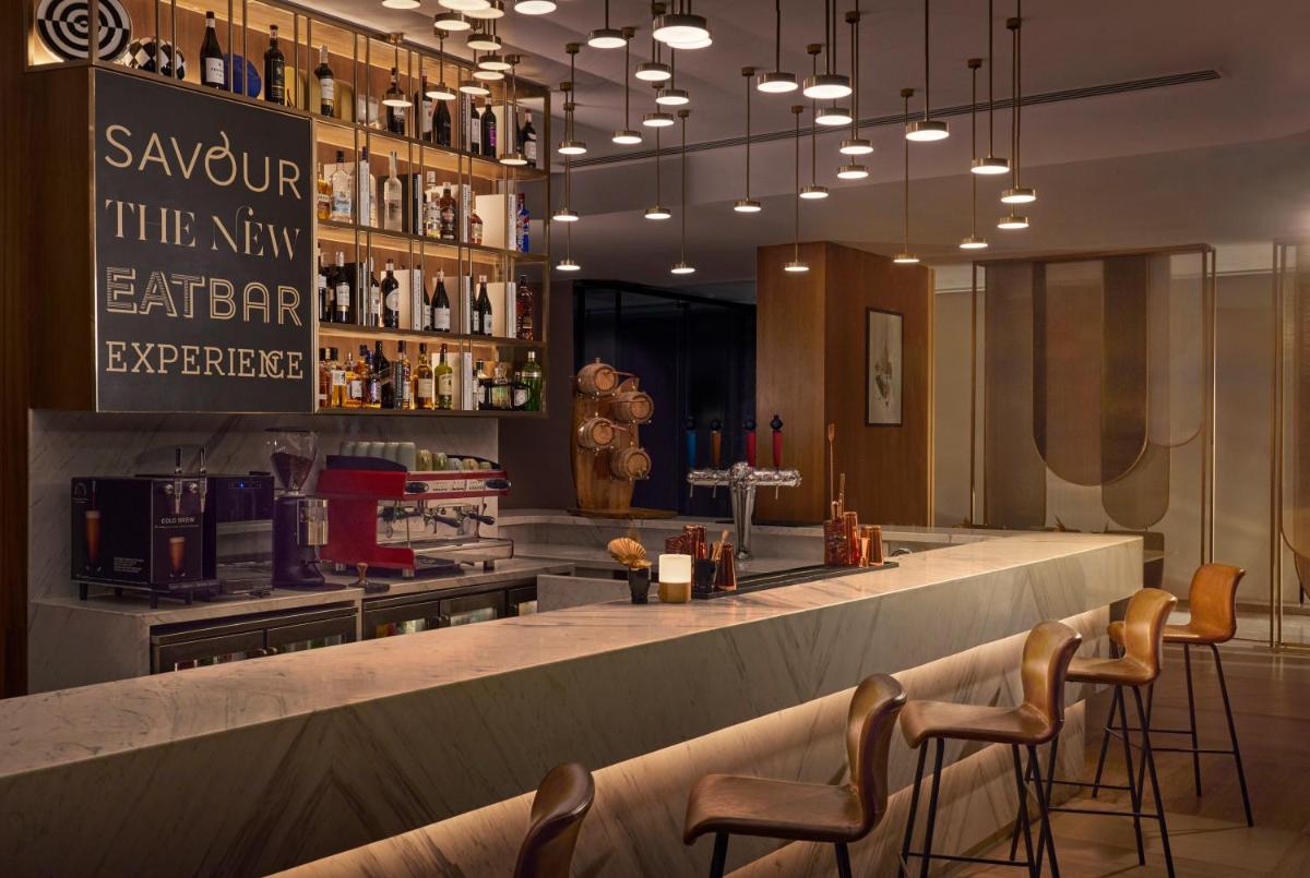 a restaurant with a bar with chairs and a counter at Novotel Mumbai International Airport in Mumbai