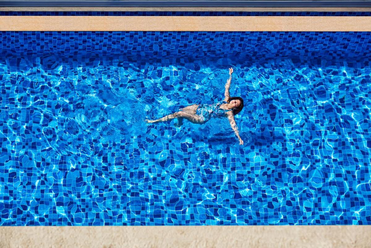 a man is swimming in a swimming pool at Novotel Mumbai International Airport in Mumbai