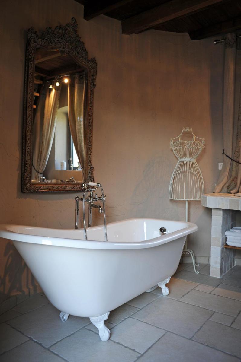 une baignoire blanche dans une salle de bain avec un miroir dans l'établissement Domaine de Suzel, à Vignieu