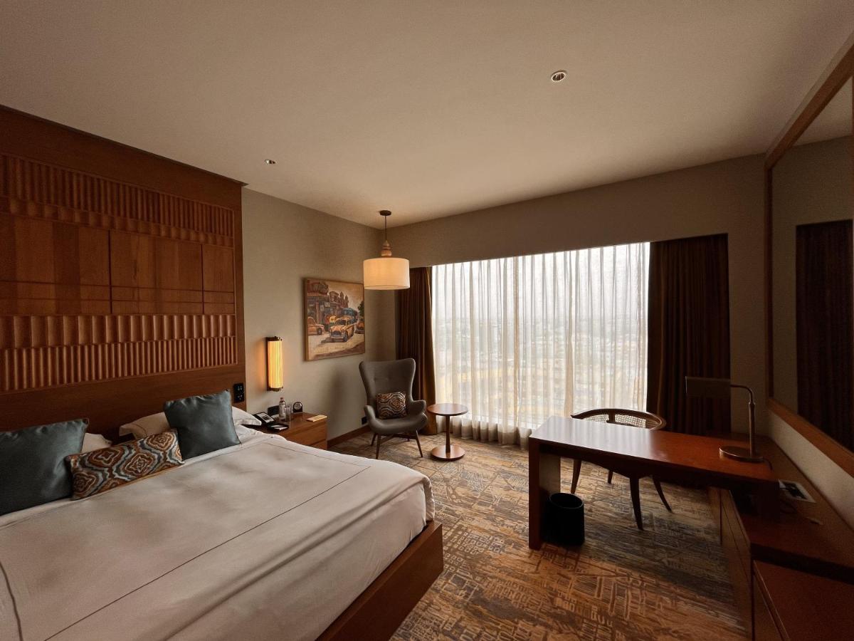 a hotel room with a bed and a desk and a window at Taj City Centre New Town, Kolkata in Kolkata a hotel room with a bed and a desk and a window at Taj City Centre New Town, Kolkata in Kolkata