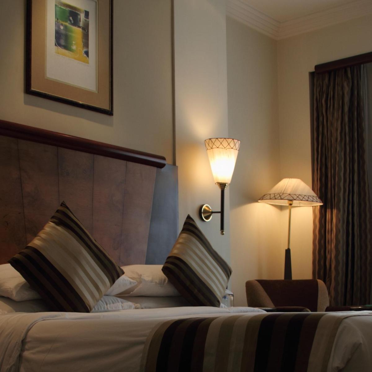 a hotel room with a bed with a lamp and a chair at The Park Kolkata in Kolkata