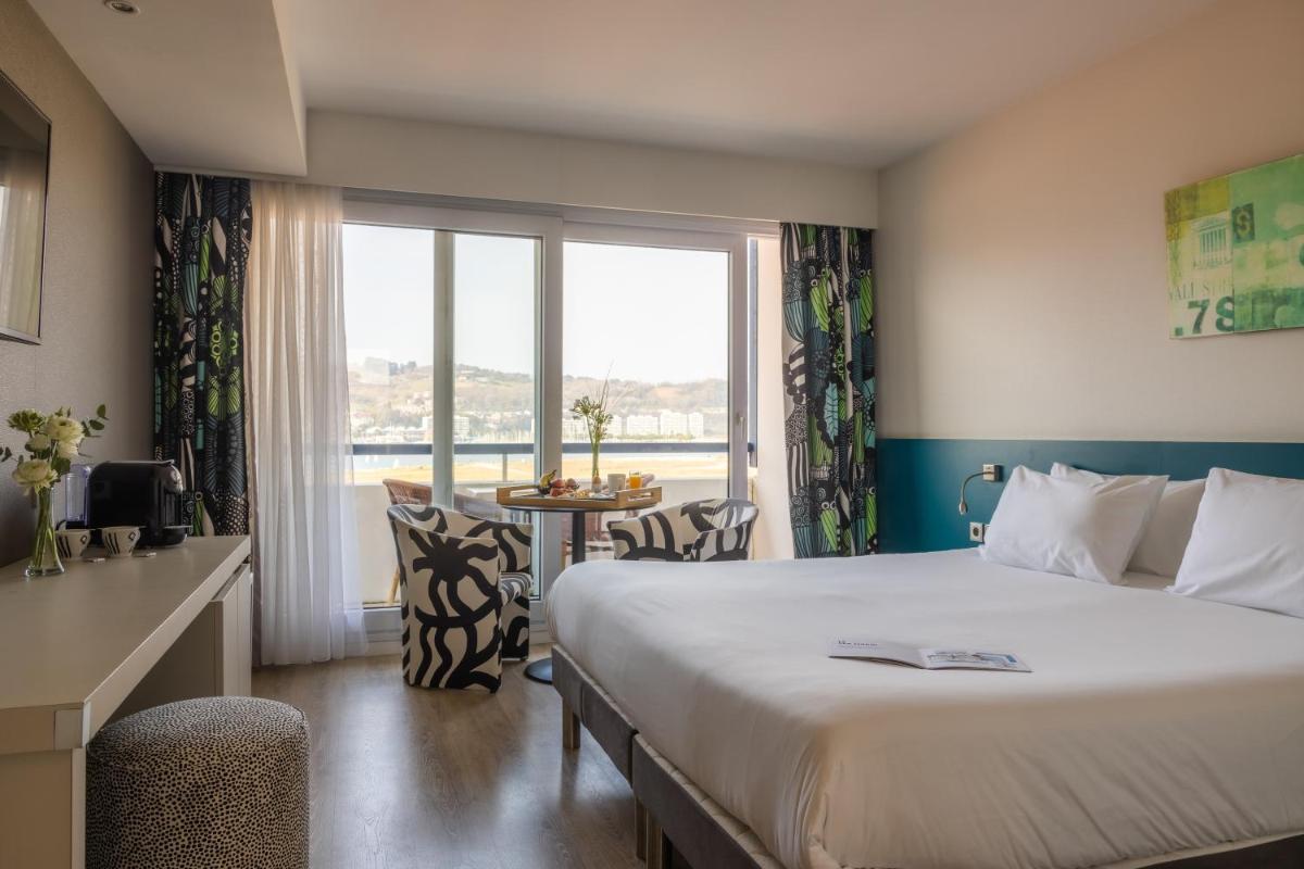 une chambre d'hôtel avec un lit et une grande fenêtre dans l'établissement Hôtel Serge Blanco - Relais Thalasso & Spa, à Hendaye