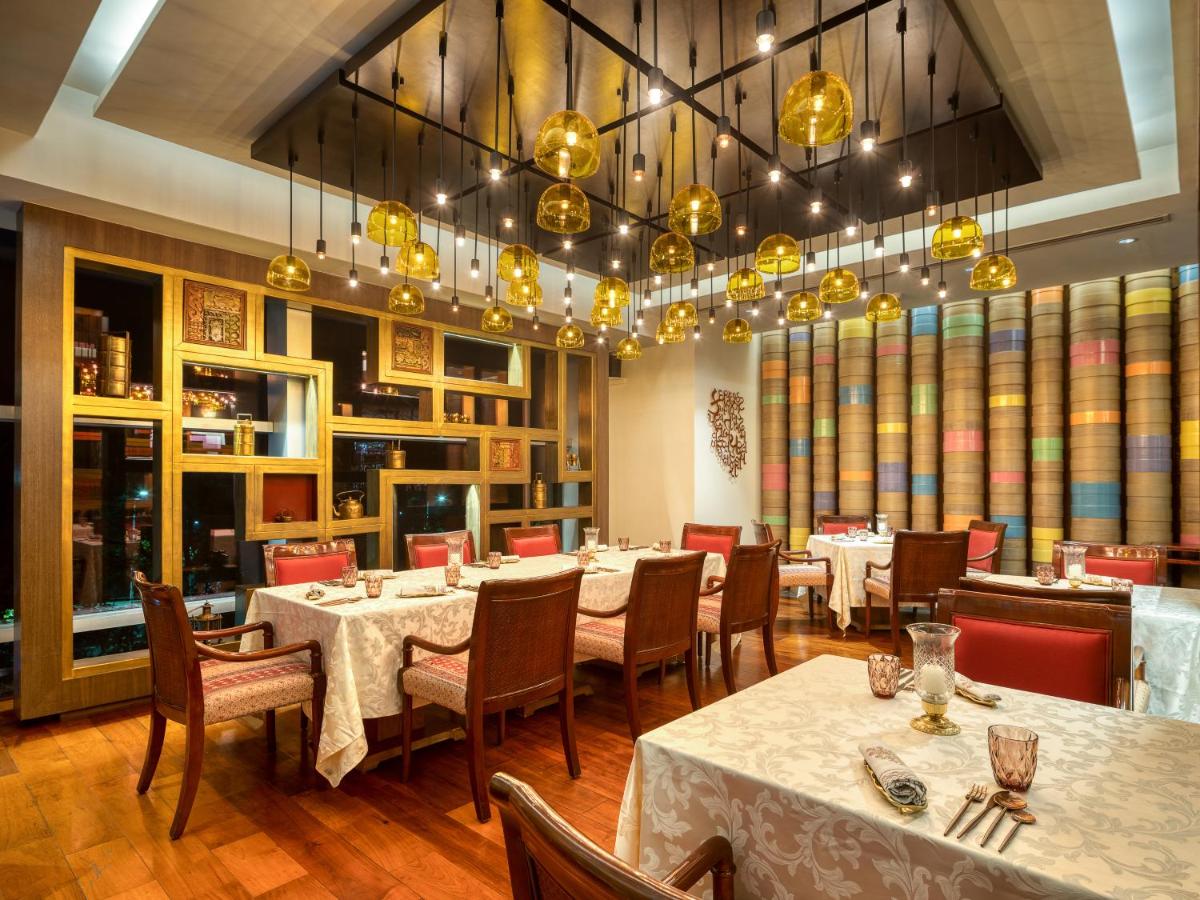 a dining room with tables and chairs and a chandelier at Hyatt Regency Ahmedabad in Ahmedabad