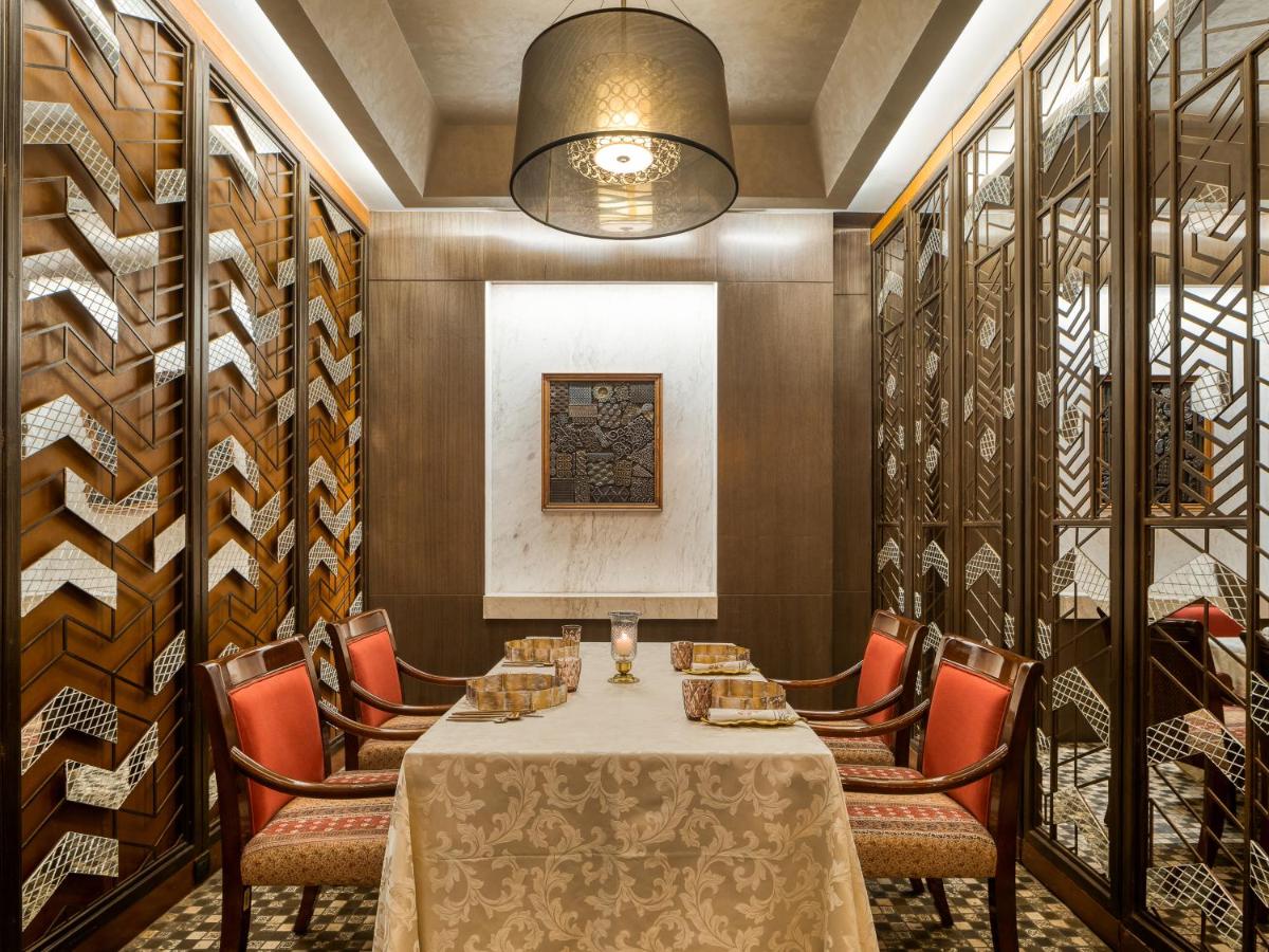 a dining room with a table and chairs and a wall of wine racks at Hyatt Regency Ahmedabad in Ahmedabad