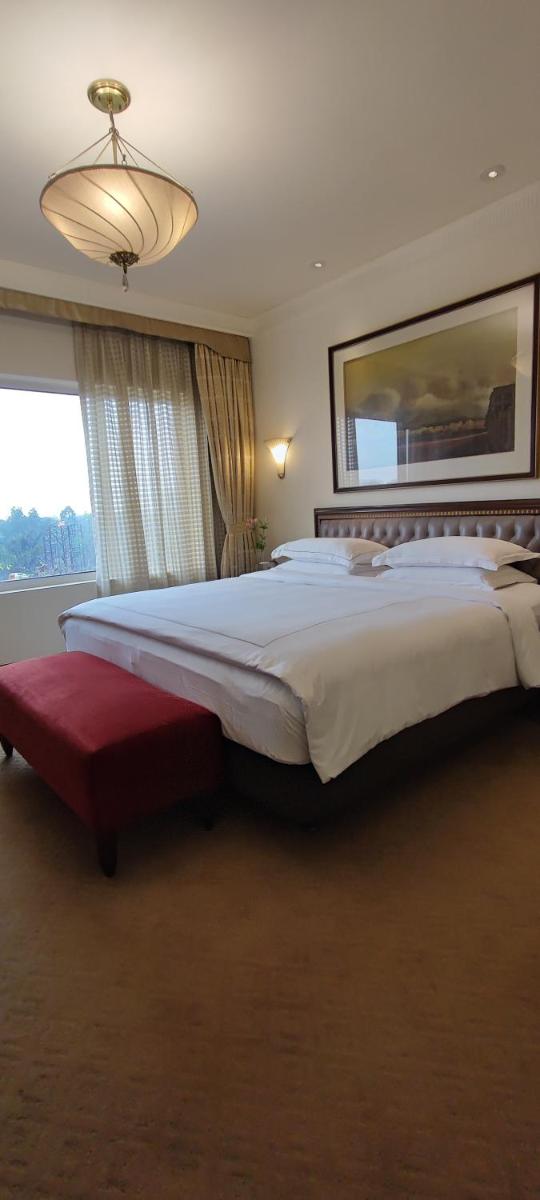 a bedroom with a large bed and a large window at Taj Bengal in Kolkata