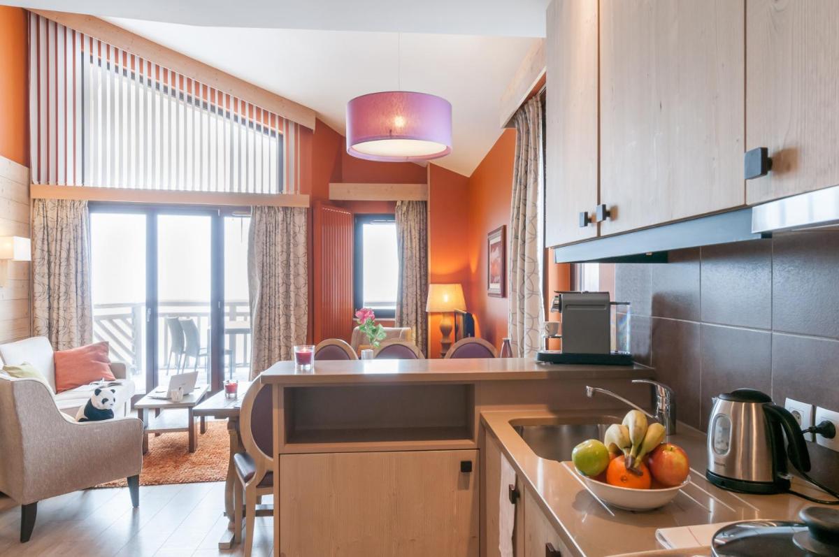 une cuisine aux murs orange et une table avec un bol de fruits dans l'établissement Résidence Pierre & Vacances Premium L'Amara, à Avoriaz 72 autres photos