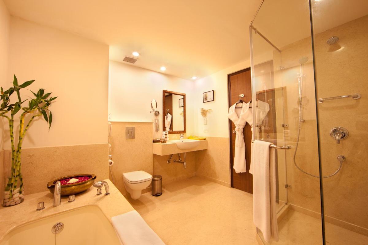 a bathroom with a shower and a tub and a sink at Lemon Tree Premier, Ulsoor Lake, Bengaluru in Bengaluru