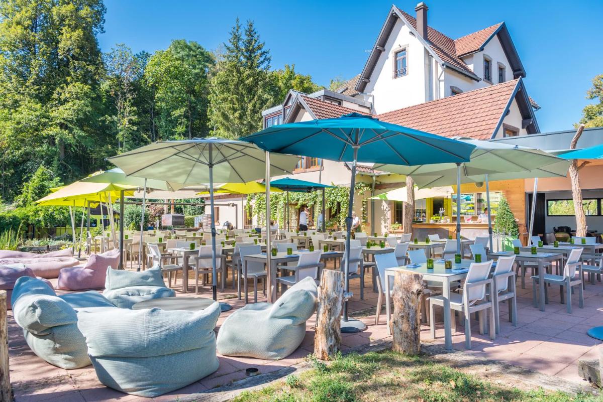 un patio avec tables, chaises et parasols dans l'établissement Hôtel La Garenne, à Saverne