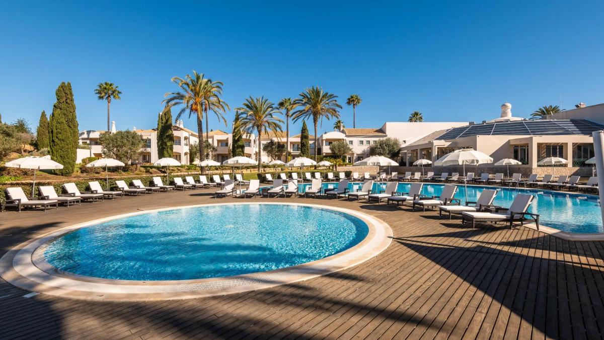 uma piscina com cadeiras e guarda-sóis em um resort em Vale d'Oliveiras Quinta Resort & Spa em Carvoeiro