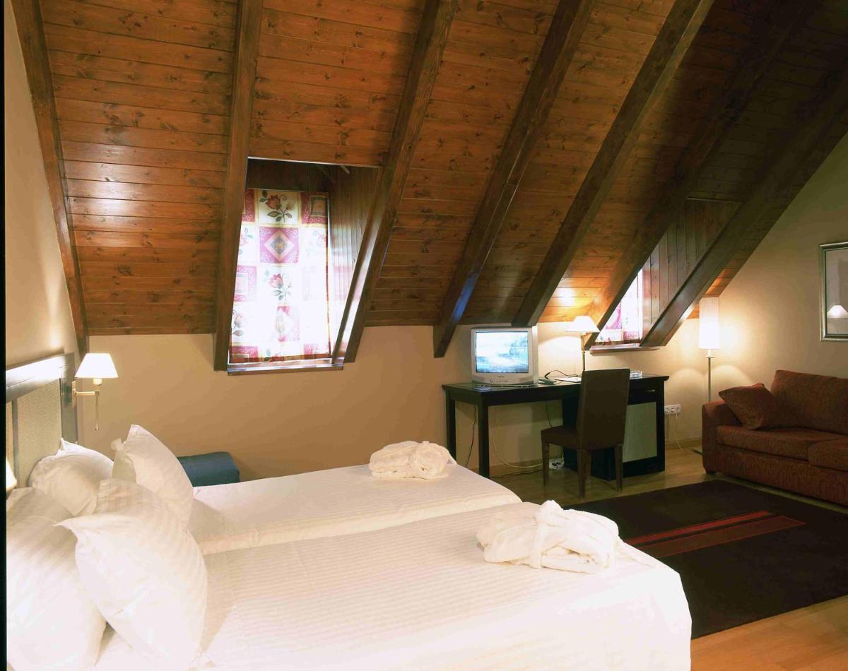 Un dormitorio con una cama y un escritorio con una computadora. en Hotel Spa Acevi Val d’Aran, en Vielha 24 fotos más