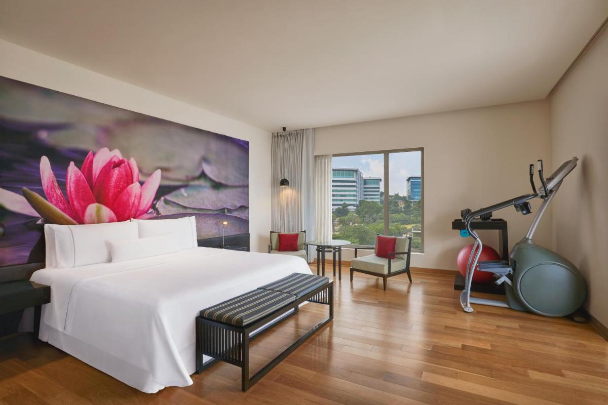 a hotel room with a large bed and a gym at The Westin Hyderabad Mindspace in Hyderabad