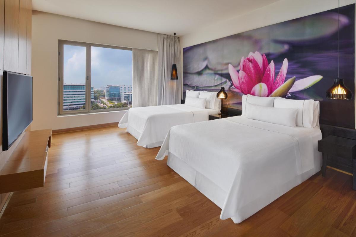 two beds in a hotel room with a large window at The Westin Hyderabad Mindspace in Hyderabad