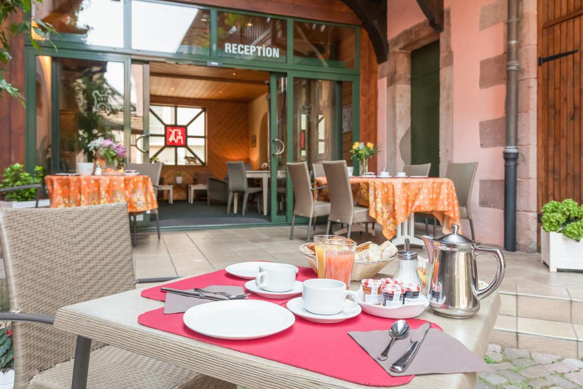 une table avec un tissu de table rouge sur une terrasse dans l'établissement Logis Hôtel de la Tour, à Ribeauvillé