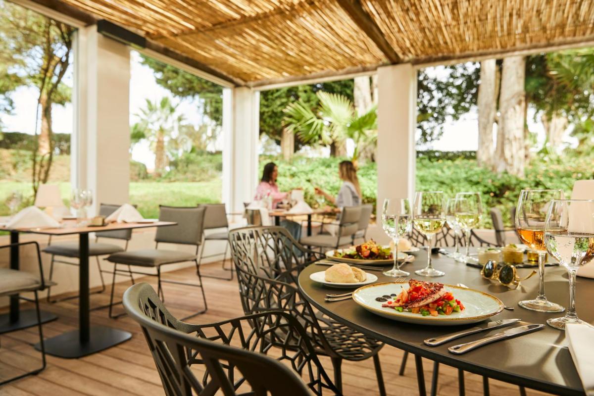um restaurante com mesas e cadeiras com comida e copos de vinho em ROBINSON QUINTA DA RIA - All Inclusive em Vila Nova de Cacela