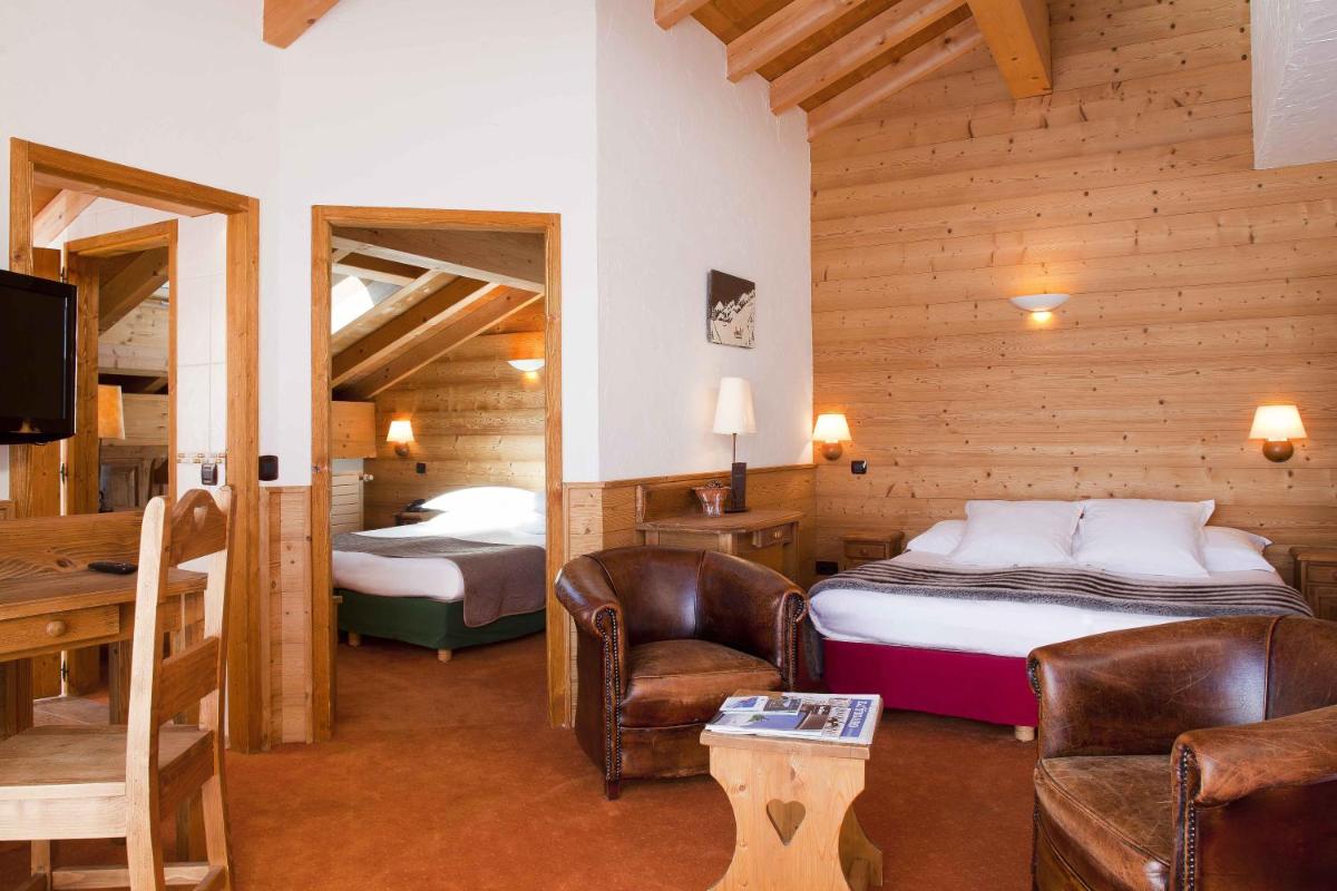 une chambre d'hôtel avec un lit, un bureau et des chaises dans l'établissement Beaulieu, à La Clusaz