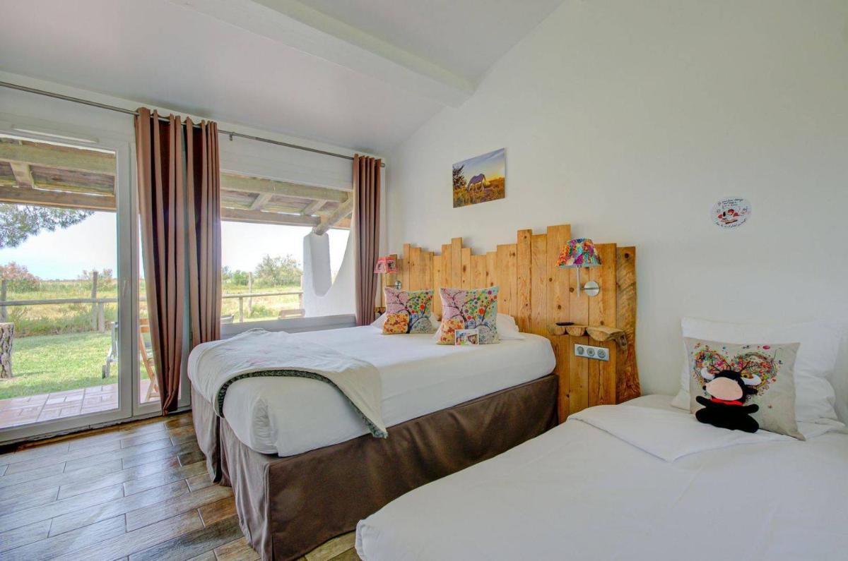 une chambre avec deux lits et une fenêtre dans l'établissement Hôtel La Palunette, à Saintes-Maries-de-la-Mer