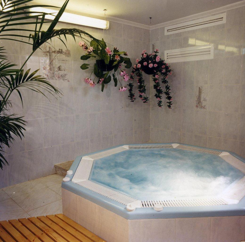 baño con bañera de hidromasaje y flores en la pared en Hotel Victoria Spa & Splay Center, en Segur de Calafell