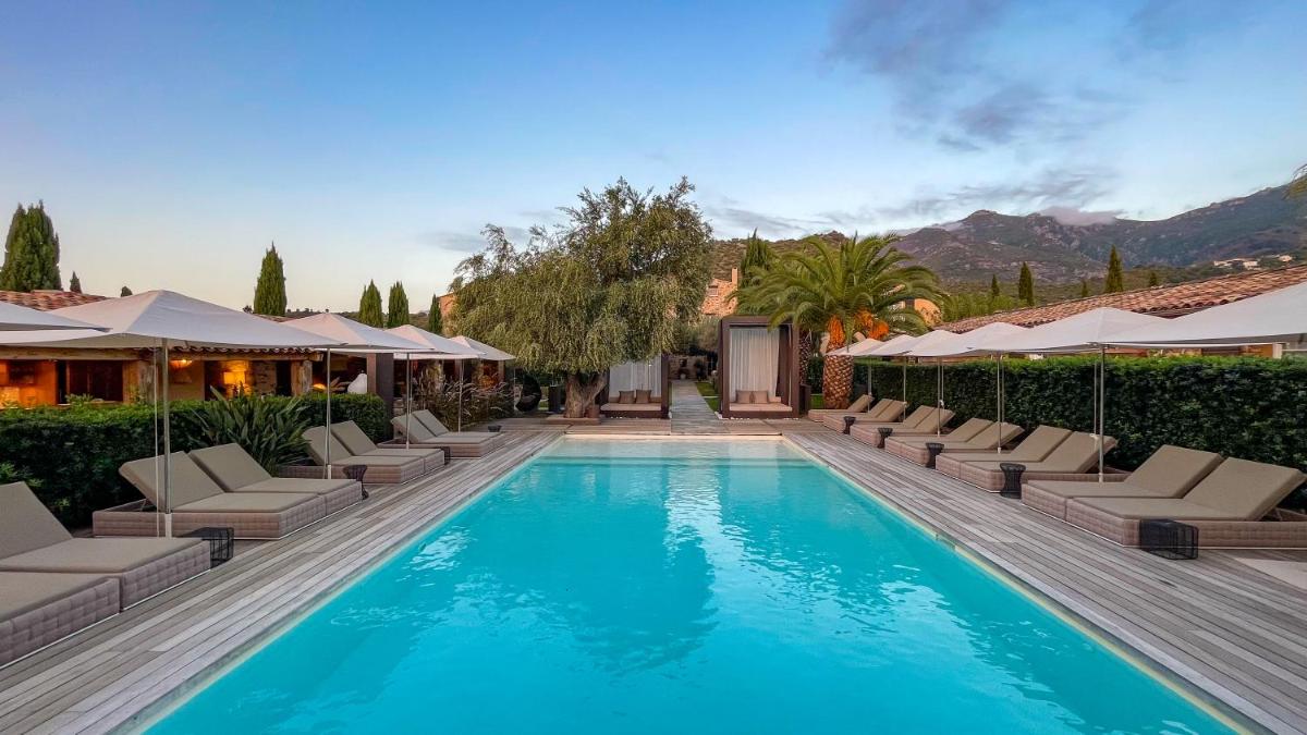 une piscine avec chaises longues et une maison dans l'établissement Hôtel La Dimora & Spa, à Saint-Florent