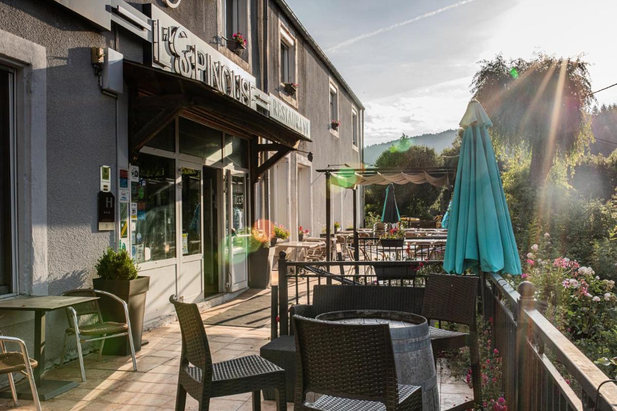 - une terrasse avec des chaises et un parasol à côté d'un bâtiment dans l'établissement Logis hôtel restaurant Auberge de l'Espinouse, à Fraisse-sur-Agout