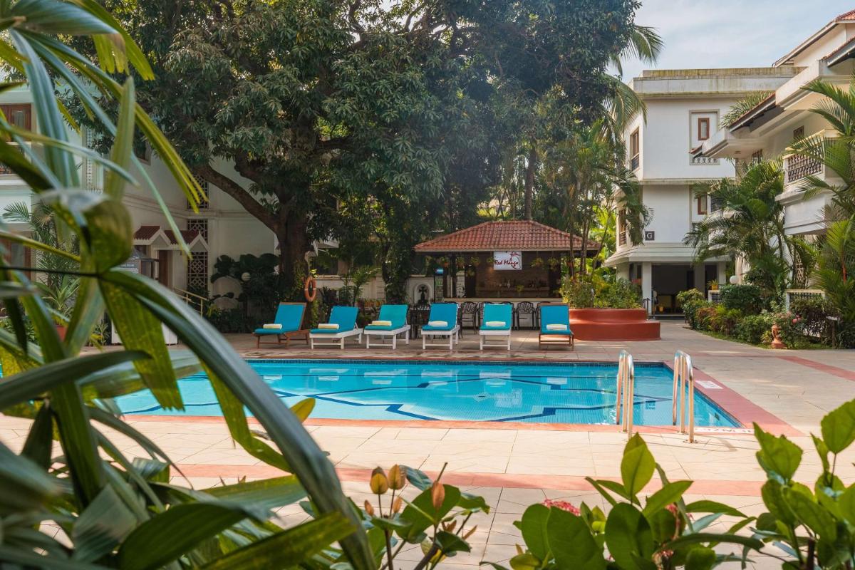 a pool with blue chairs and a gazebo at Radisson Goa Candolim in Candolim