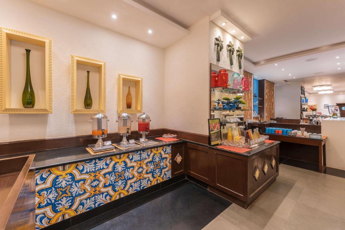 a restaurant with a counter with vases on the wall at Radisson Goa Candolim in Candolim