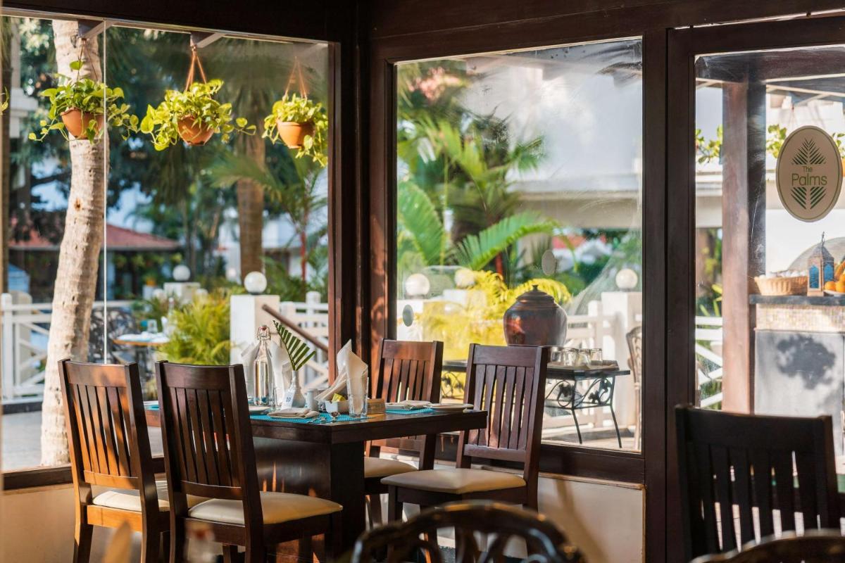 a restaurant with a table and chairs and a window at Radisson Goa Candolim in Candolim