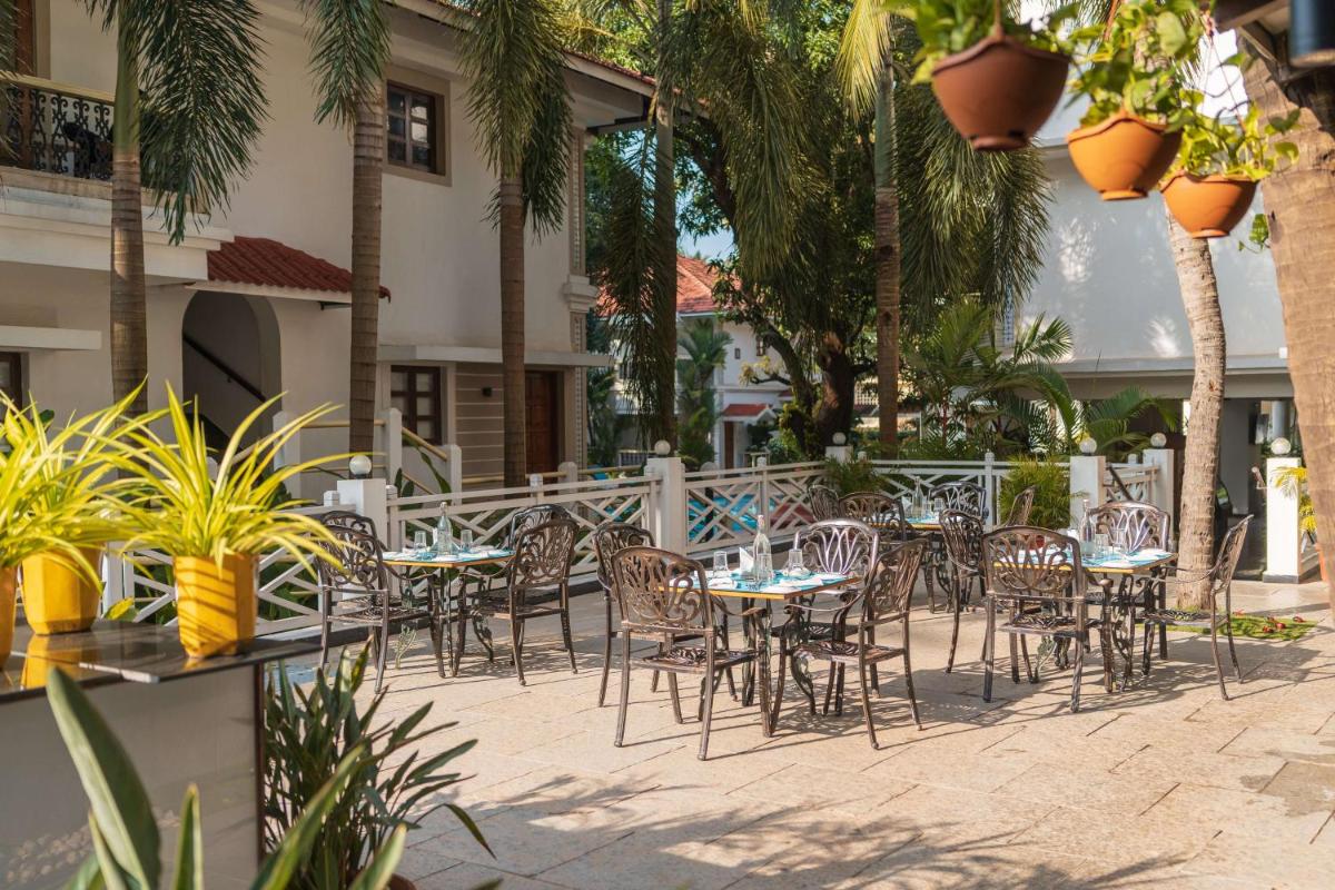 a patio with tables and chairs and palm trees at Radisson Goa Candolim in Candolim