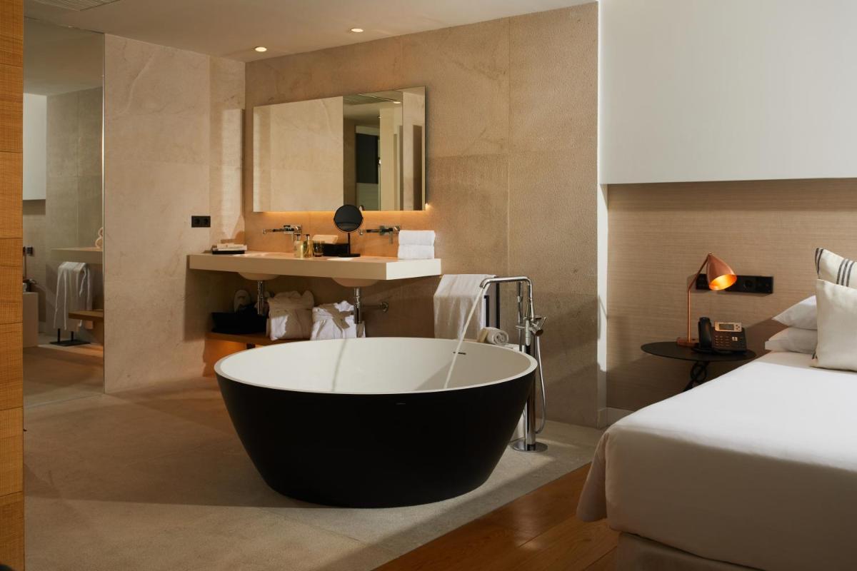 Un baño con bañera al lado de una cama. en Nakar Hotel, en Palma de Mallorca