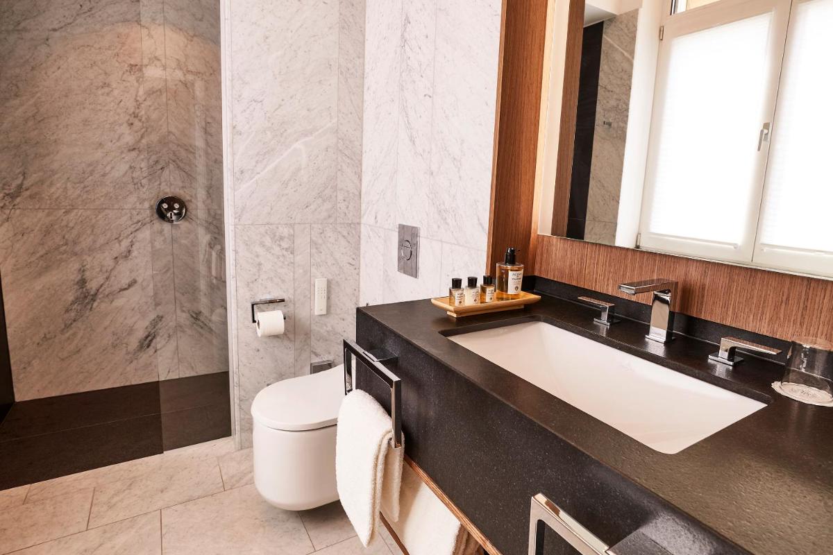 ein Badezimmer mit Waschbecken, Toilette und Spiegel in der Unterkunft Steigenberger Icon Parkhotel Düsseldorf in Düsseldorf