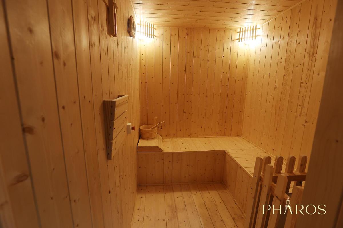 a sauna with a tub in a wooden room at Pharos Hotels in Chennai