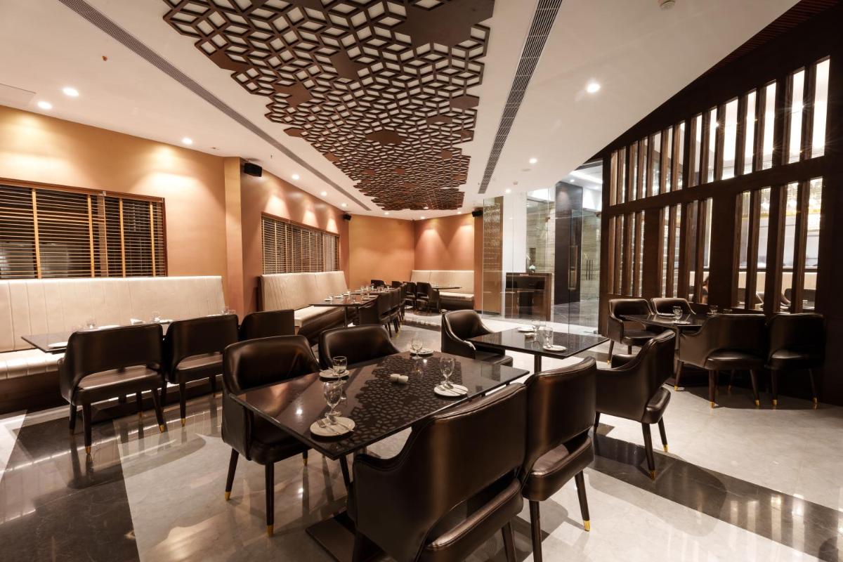 a restaurant with black tables and chairs and windows at Pharos Hotels in Chennai