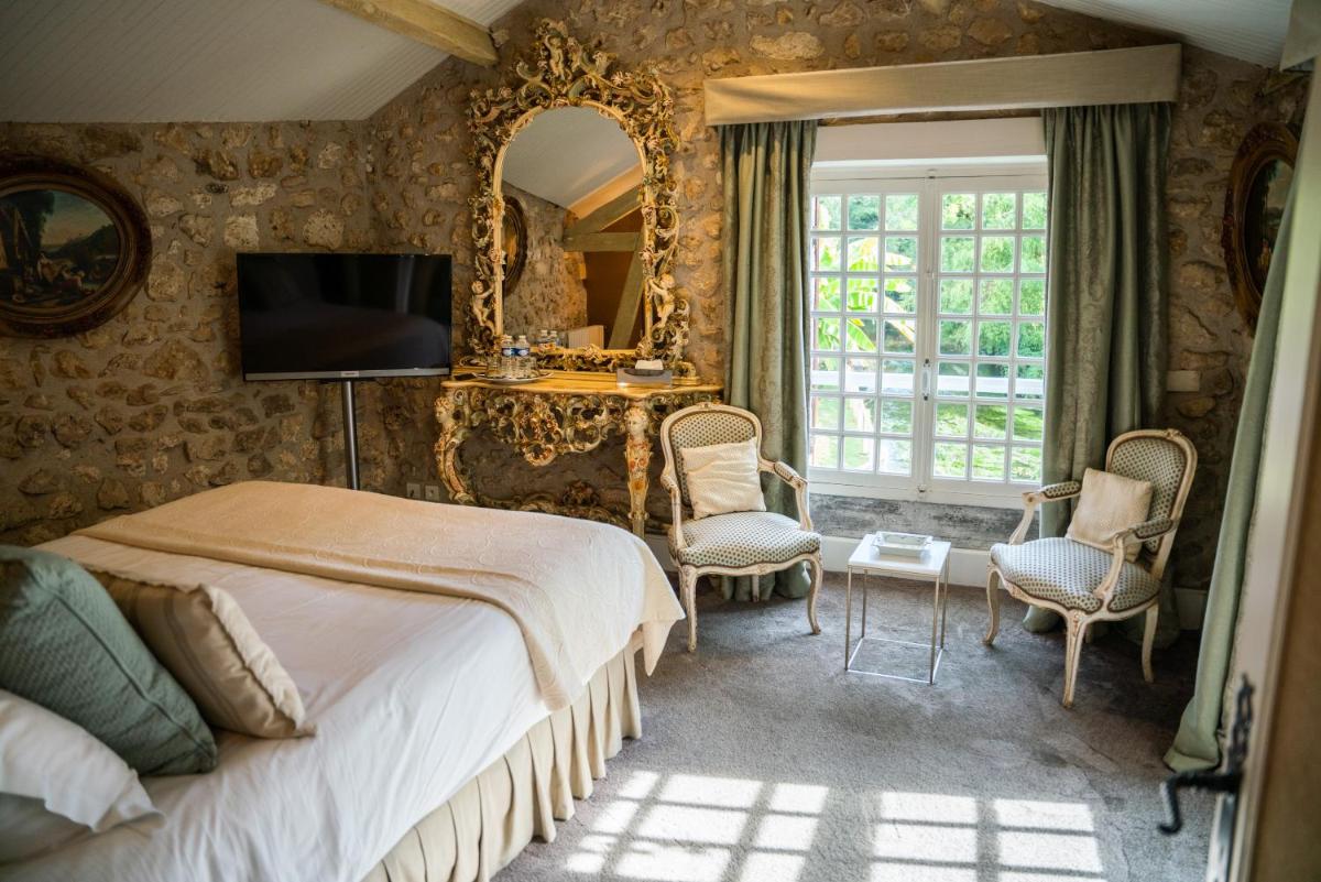 une chambre avec un lit et un miroir dans l'établissement Le Moulin du Roc, à Brantôme 28 autres photos