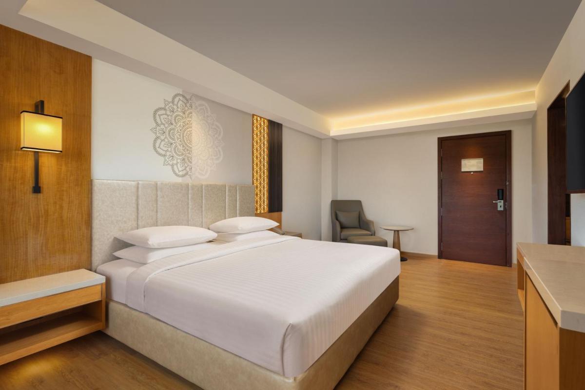 a bedroom with a large white bed and a chair at Courtyard by Marriott Tiruchirappalli in Tiruchchirāppalli