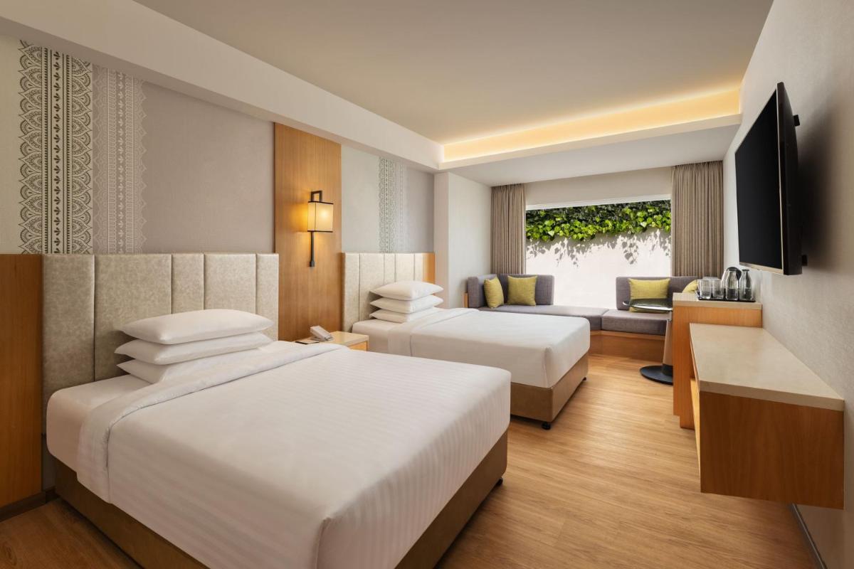 a hotel room with two beds and a couch at Courtyard by Marriott Tiruchirappalli in Tiruchchirāppalli