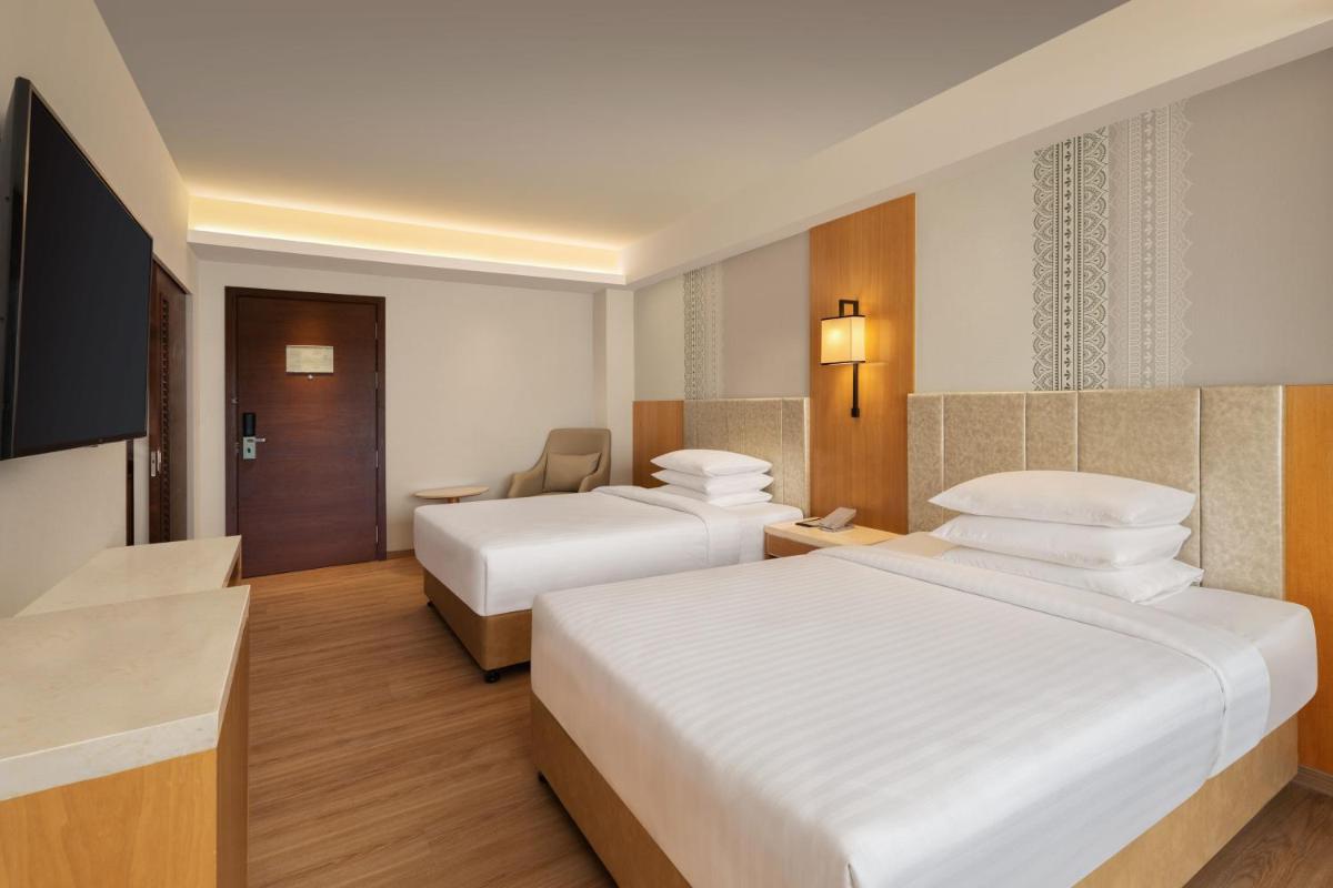 a hotel room with two beds and a television at Courtyard by Marriott Tiruchirappalli in Tiruchchirāppalli