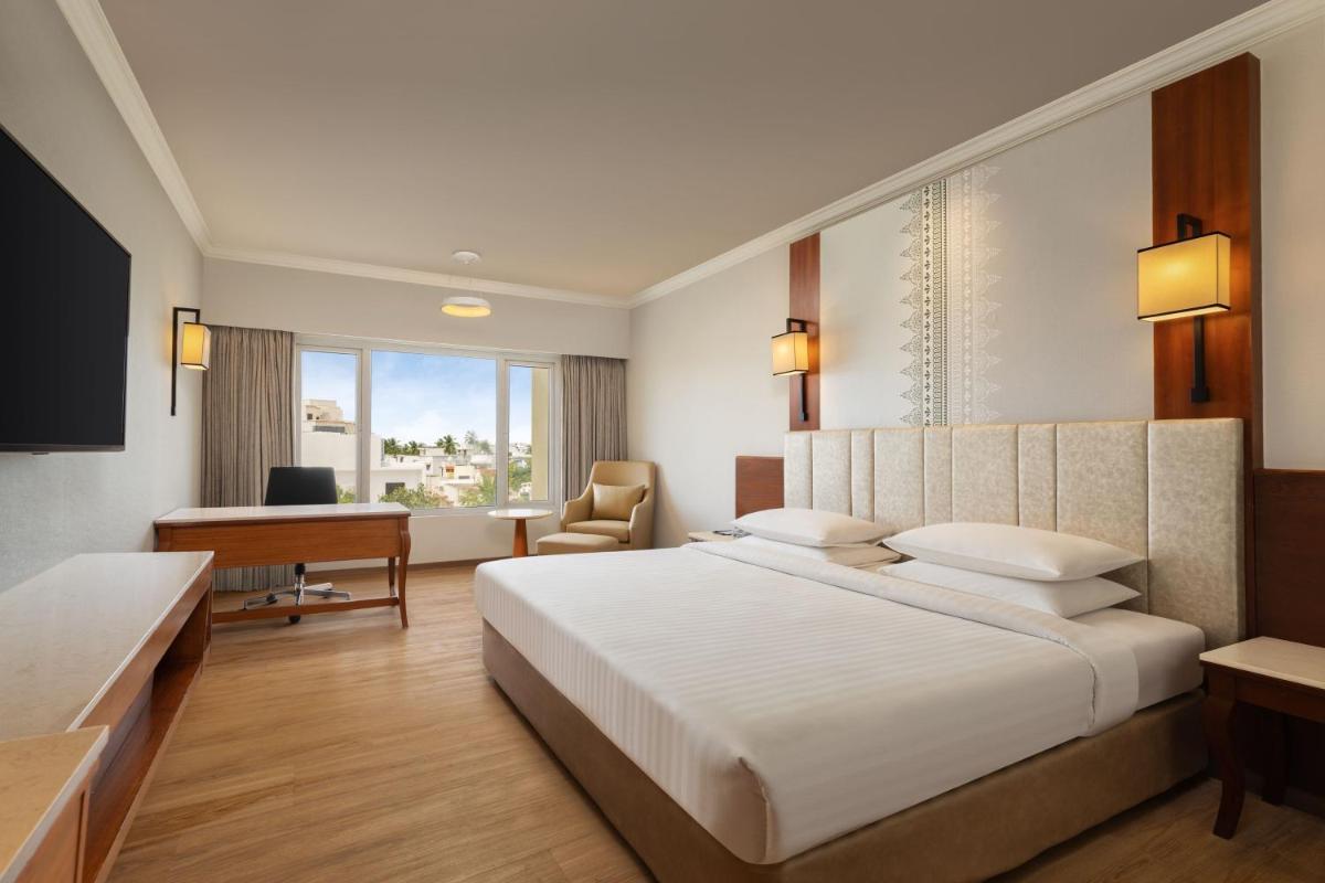 a bedroom with a large white bed and a desk at Courtyard by Marriott Tiruchirappalli in Tiruchchirāppalli