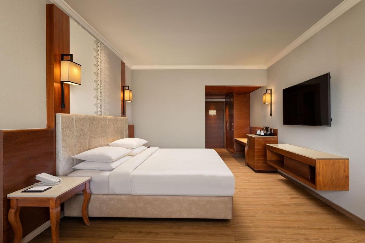 a hotel room with a bed and a television at Courtyard by Marriott Tiruchirappalli in Tiruchchirāppalli