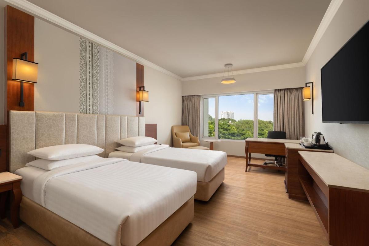 a hotel room with two beds and a desk at Courtyard by Marriott Tiruchirappalli in Tiruchchirāppalli
