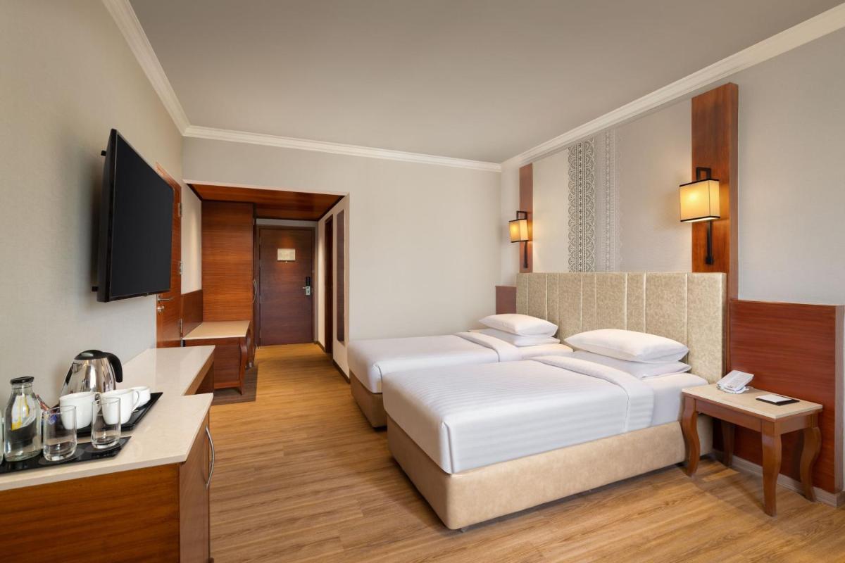 a hotel room with two beds and a television at Courtyard by Marriott Tiruchirappalli in Tiruchchirāppalli