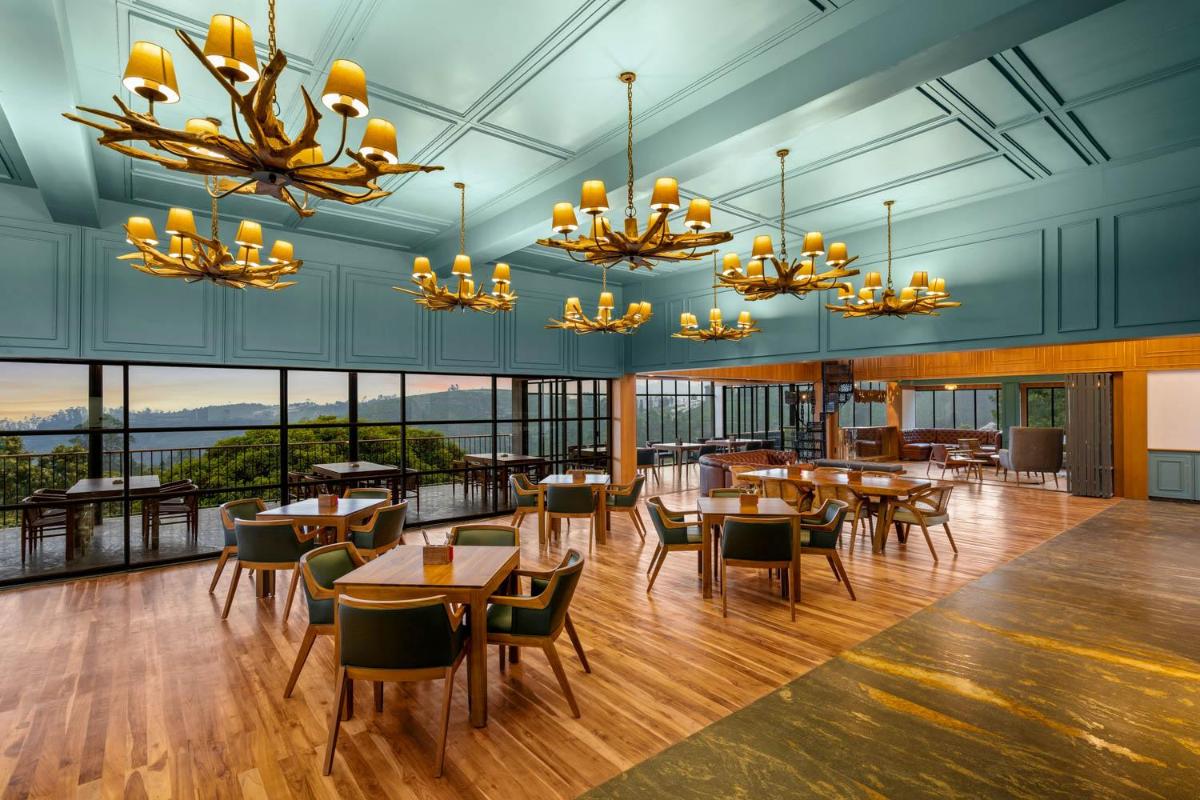 a dining room with tables and chairs and windows at WelcomHeritage Ayatana Ooty in Ooty