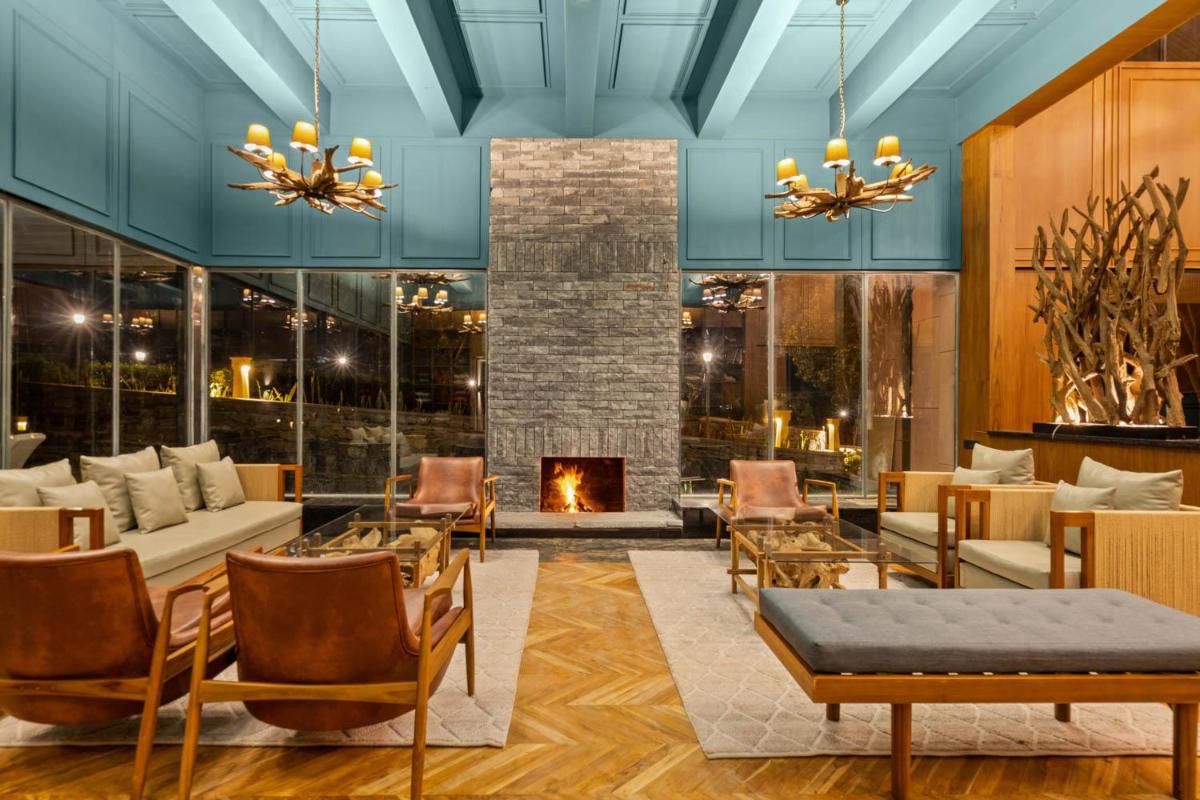 a living room with a fireplace and furniture at WelcomHeritage Ayatana Ooty in Ooty