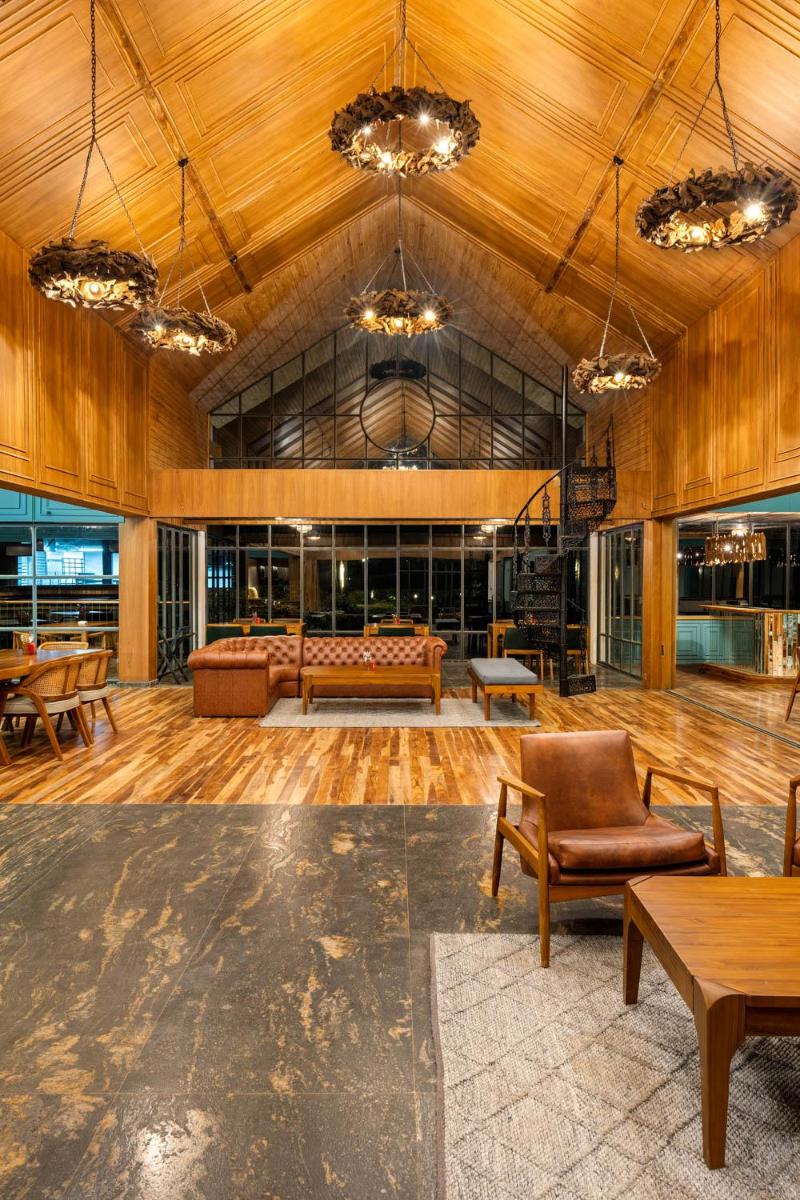 a large room with wooden floors and tables and chairs at WelcomHeritage Ayatana Ooty in Ooty