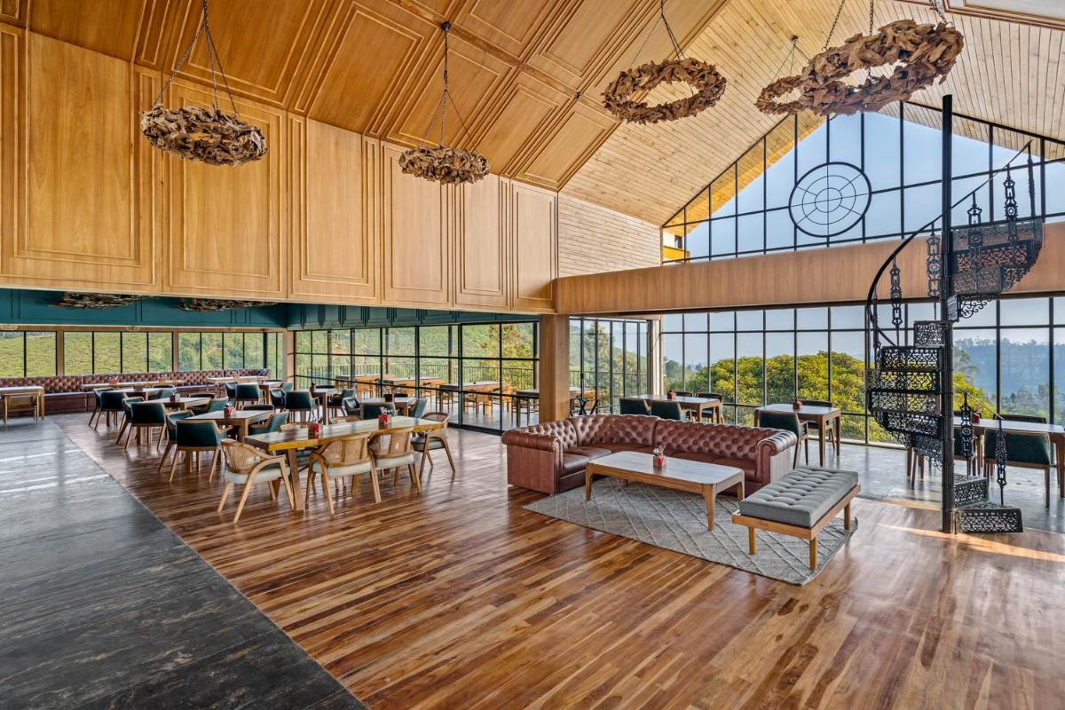 a large lobby with tables and chairs and windows at WelcomHeritage Ayatana Ooty in Ooty