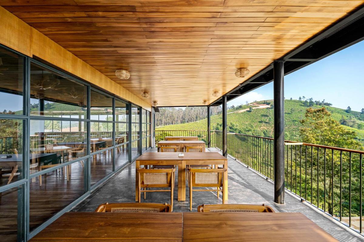 a restaurant with wooden tables and chairs on a balcony at WelcomHeritage Ayatana Ooty in Ooty
