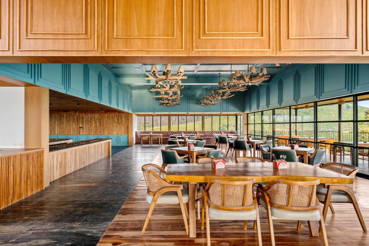 a dining room with wooden tables and chairs at WelcomHeritage Ayatana Ooty in Ooty