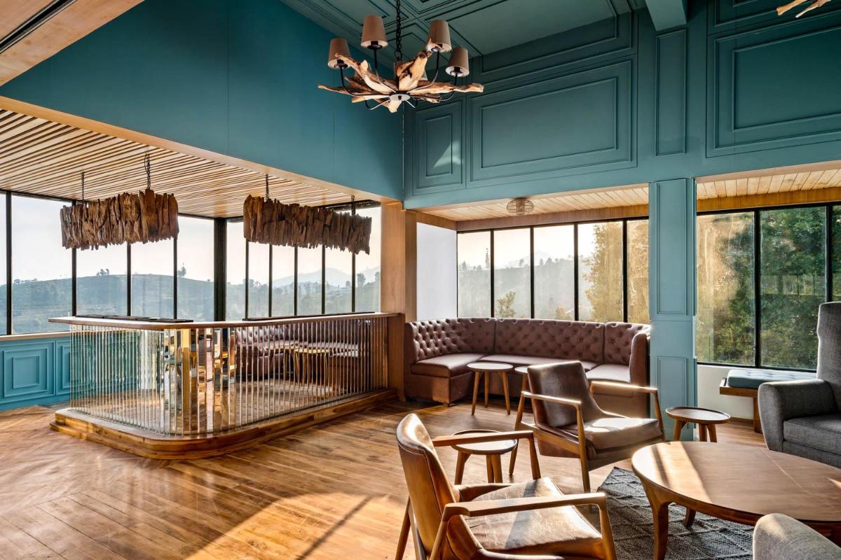 a living room with a couch and tables and windows at WelcomHeritage Ayatana Ooty in Ooty