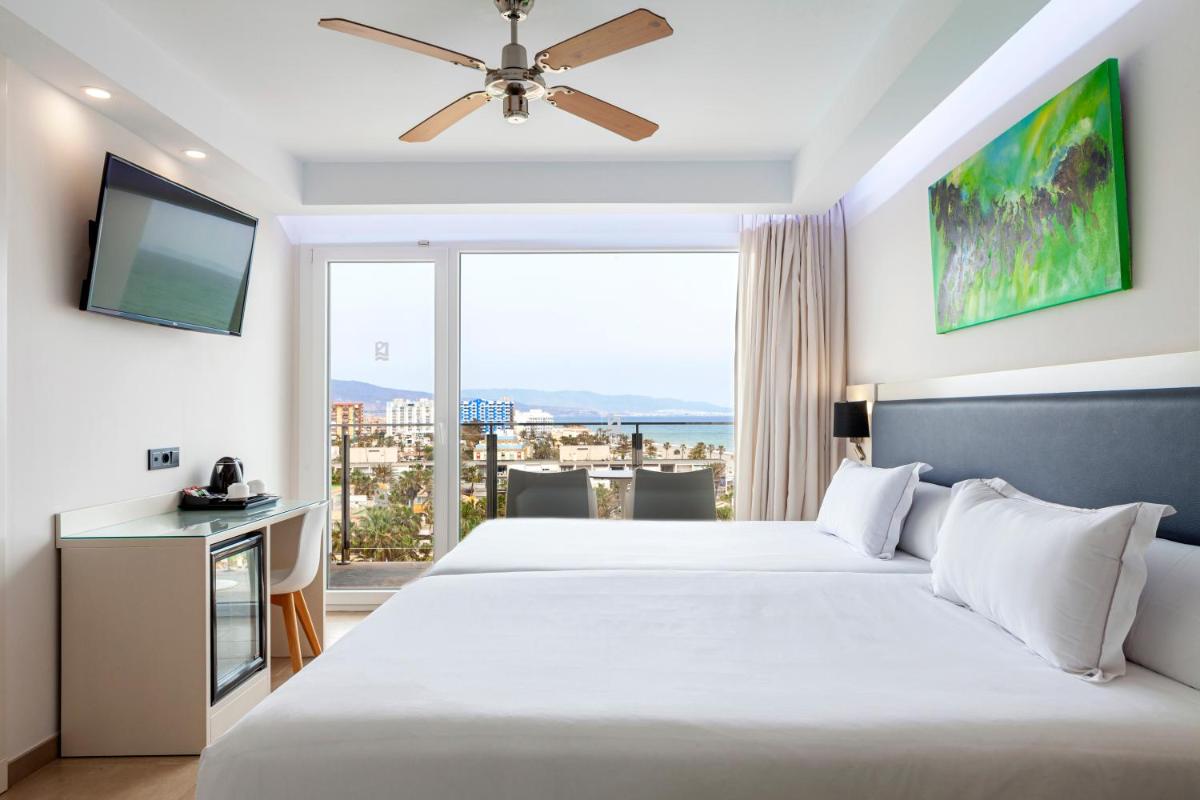 Un dormitorio con una cama grande y una ventana grande. en Playasol, en Roquetas de Mar