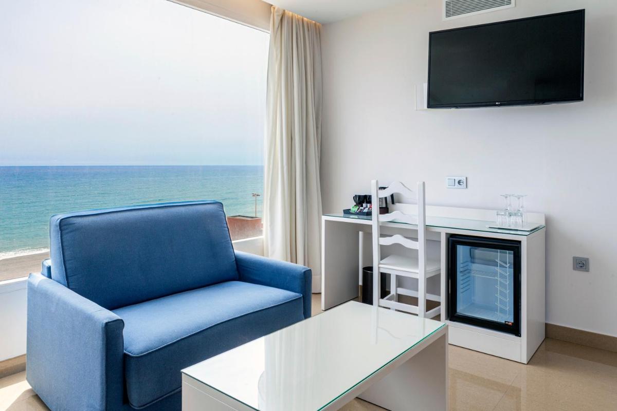 sala de estar con silla azul y TV en Playasol, en Roquetas de Mar